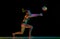 Young competitive woman, volleyball player in motion, training, hitting ball against black studio background in neon