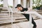 Young concentrated athletic beautiful brunette girl in black uniform and cap doing sport exercises, making push-up warm