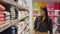 Young concentrated female customer choosing bath towel in home goods department