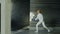 Young concentrated fencer woman practice fencing exercises and training for Olympic games competition in studio indoors
