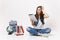 Young concerned woman student holding using tablet pc computer keeping hand on head sitting near globe, backpack school