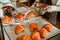 Young confectioner with bowl of cream makes croissant with filling at countertop