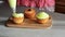 Young confectioner decorates cupcakes with lemon cream and grape close up