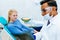 Young confident asian male dentist checking teeth x ray of patient. Dental clinic concept.