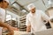 young confident bakers working with industrial dough roller