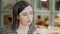 Young confident brunette Caucasian woman talking with unknown friend sitting in urban restaurant on sunny day. Close-up