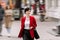 Young confident businesswoman in formalwear, red jacket is talking on smartphone while walking on city street