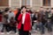 Young confident businesswoman in formalwear, red jacket is talking on smartphone while walking on city street