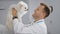 Young, confident caucasian man smiles as he stands with his cute dog at the vet\\\'s clinic, happy with the diligent care and