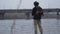 Young confident fisherman in khaki pants in the early morning spinning fishing in river near the city. Fishing rod and a