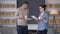 Young confident interracial couple standing in living room with coffee cups discussing business strategy in home office