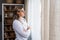 Young confident woman psychologist looking out the window from home office. Female mental health worker taking a break after