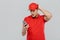 Young confused delivery man wearing uniform using mobile phone