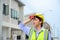 Young construction engineer woman wearing safety helmet wipes sweat on her face. Tired heat and hot at building construction site