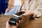 Young consumer holding smartphone over payment machine held by shop assistant