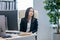 Young contemporary businesswoman sitting by workplace