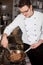 Young cook preparing steak in a pan