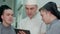 Young cook trainees having discussion with chef holding tablet