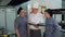 Young cook trainees having positive discussion with chef holding cookbook