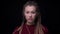 Young cool brunette girl with piercing and dreadlocks watches calmly and fixedly into camera on black background.