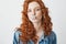 Young cool brutal redhead girl in jean jacket chewing gum looking at camera over white background.