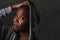 Young cool and serious black African American woman with head shaved posing confident and playful isolated on dark background