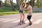 Young cool tattooed man teaching his girfriend how to skateboarding.