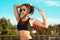 Young cool woman holding hair. Fashionable girl in a sports tank top and sunglasses on the background of azure sky. Swag girls.