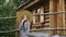 Young country girl in hat posing on wooden rustic house background. Beautiful teenager girl in hat standing on timbered