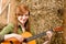 Young country woman playing guitar in barn