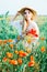 Young countryside girl sitting in the field of poppies