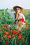 Young countryside girl sitting in the field of poppies