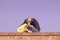 Young couple 20s kissing sitting brick wall