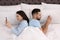 Young couple addicted to smartphones in bed at home