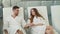 Young couple attractive woman and handsome man in bathrobes are sitting in relaxation room in day spa, holding hands and