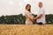 Young couple awaiting baby among the wheat field