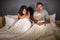 Young couple in bed scared and stressed after positive result on pregnancy test with pregnant woman expecting unwanted baby and ma