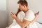 Young couple in the bedroom. Side view of unfaithful man and woman are cheating on the phone while hugging each other