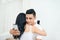 Young couple in the bedroom. Smiling unfaithful man is cheating and texting lover on the phone while hugging his girlfriend