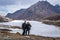 Young couple biker at frozen lake with mountain valley background at day