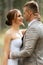 young couple bride in a white short dress and groom in a gray suit in a pine forest