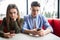 Young couple in cafe looking at their smartphones, social network concept