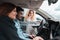 Young couple in car. Female dealership consultant shows a car to a young couple. Young family chooses auto at a car dealership