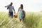 Young Couple Carrying Picnic Basket And Windbreak