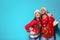 Young couple in Christmas sweaters and knitted hats on color background.