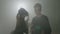 Young couple of college students dressed up as zombies on a background with fog getting ready for halloween party -