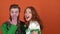 Young couple in costumes celebrating saint patrick`s day isolated on orange wall close-up girl kissing guy