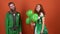 Young couple in costumes celebrating Saint Patrick`s Day isolated on orange wall gift