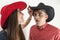 Young couple with cowboy hats and glasses making silly faces on white