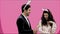 Young couple creative on pink background. With a bunny ears on the head. During this, the wife holds decorative